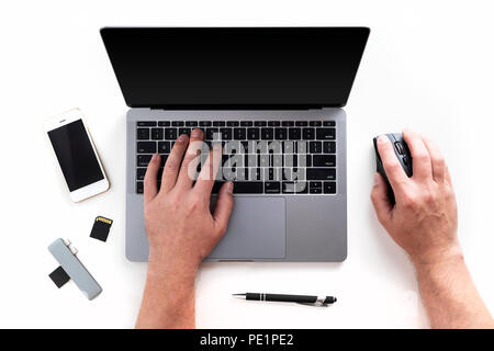 Vue de dessus de mains d'homme sur un ordinateur portable, téléphone mobile, cartes mémoire, lecteur de carte, stylet et souris isolé sur fond blanc Banque D'Images