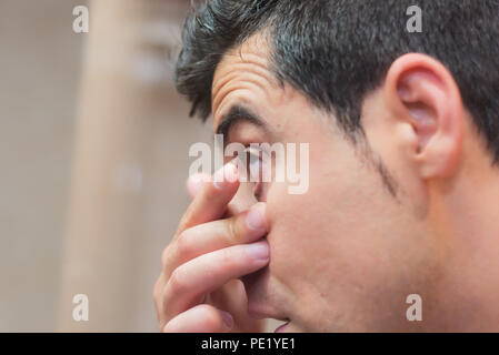 Jeune homme de mettre dans son oeil de verre de contact Banque D'Images