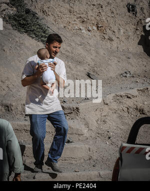 Idlib, en Syrie. 10 août, 2018. Un homme est vu porter un bébé.9 militants anti Gouvernement sont morts et plus de 45 blessés à la suite d'un intense bombardement de la ville de Khan Shikhon par le régime syrien, l'aviation et de l'hélicoptère. Credit : Anas Aldyab SOPA/Images/ZUMA/Alamy Fil Live News Banque D'Images