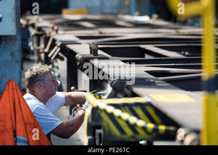 Wittenberge, Allemagne. Le 13 juillet, 2018. Un employé de l'atelier de filiale DESAG Schienenfahrzeugbau Wittenberge (SFW) pulvérise un nouveau numéro de voiture sur un wagon de marchandises réparées. En 170 ans, la locomotive, l'un des plus importants des entreprises de fret ferroviaire en Allemagne exploite un atelier moderne. Credit : Jens Büttner/dpa-Zentralbild/dpa/Alamy Live News Banque D'Images