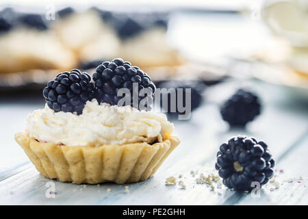 Mini tartelettes mûres avec la crème fouettée et du café. Banque D'Images