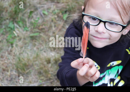 Une petite fille tenant une plume dans sa main Banque D'Images