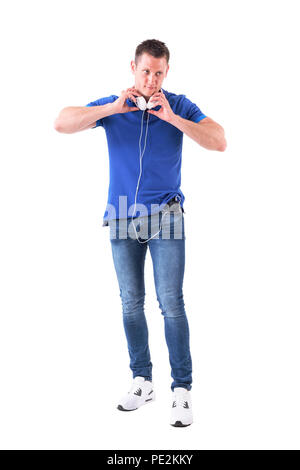 Jeune homme tenant un casque autour du cou relié au téléphone intelligent à la route. Corps plein isolé sur fond blanc. Banque D'Images