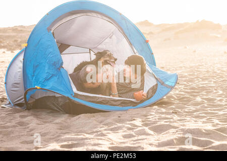 Couple dans une activité de loisirs camping libre de s'amuser à l'intérieur petite maison à la plage. Chien border collie derrière eux avec l'amour et l'amitié pour toujours Banque D'Images