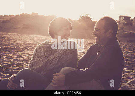 Belle belle moyen age 40 ans couple homme et femme caucasian embrassé et rester ensemble sur la plage assis dans le sable et bénéficiant d'un un golde Banque D'Images