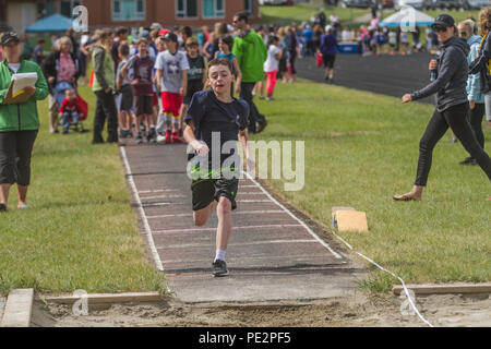 Jeune garçon en compétition dans track & field's trple saut, vêtus de t-shirt et un short. L'exécution pour le décollage. Parution du modèle Banque D'Images