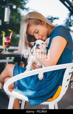 Jeune fille blonde dans la cafétéria tenue adorable chiot bouledogue français. Banque D'Images