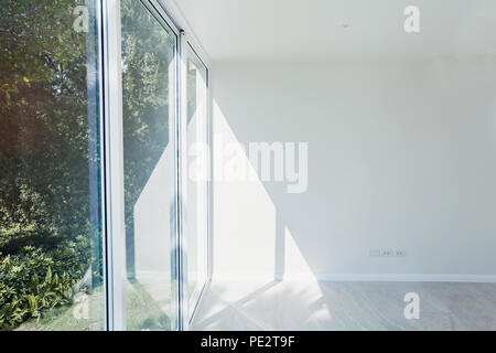 Chambre ensoleillée vide intérieur avec des murs peints en blanc, grande fenêtre et plancher plancher en bois moderne, appartement neuf en construction Banque D'Images