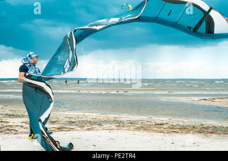 Kitesurfer pompage se remplit d'air son cerf-volant à l'aide de pompez avec des cerfs-volants dans le ciel bleu intense de la tempête l'arrière-plan dans un temps orageux Banque D'Images