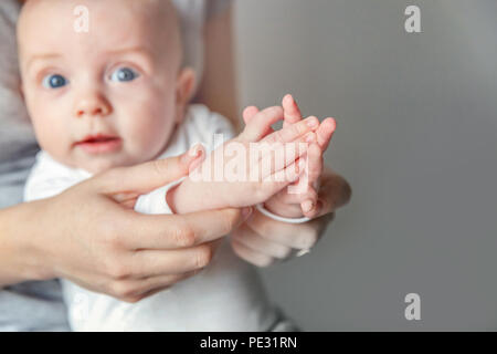 Jeune mère et nouveau-né de l'applaudir leurs mains. Femme et enfant nouveau né garçon se détendre et jouer sur fond blanc. La famille, la maternité, la tendresse, p Banque D'Images