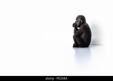 Réfléchis isolé seul singe, monkey, statuette sur fond blanc Banque D'Images