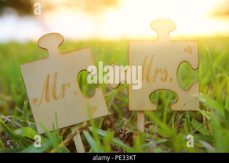 M. et Mme signe. Deux pièces du puzzle placés dans l'herbe pendant l'heure du coucher du soleil et l'harmonie. concept de mariage Banque D'Images