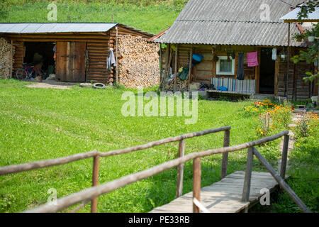 Ancienne maison rurale en bois dans une zone montagneuse dans les Carpates. Bâtiment traditionnel. Cour avec l'herbe verte. Banque D'Images