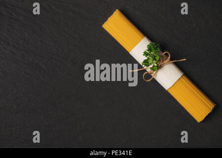 Les pâtes spaghetti sec attaché avec une corde sur la table en bois foncé Banque D'Images