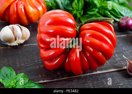 Une grande fruits rouges au basilic tomates sur une table en bois. Variété de tomate italienne. Banque D'Images