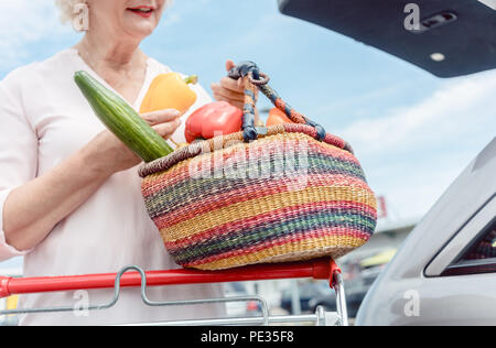 Cheerful senior femme tenant un panier plein de légumes frais Banque D'Images