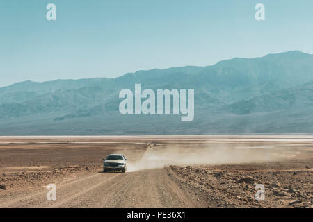 Road Trip dans le désert. Conduite de voiture sur un chemin de piste avec de la poussière dans la Death Valley National Park en été, en Californie, USA. Banque D'Images