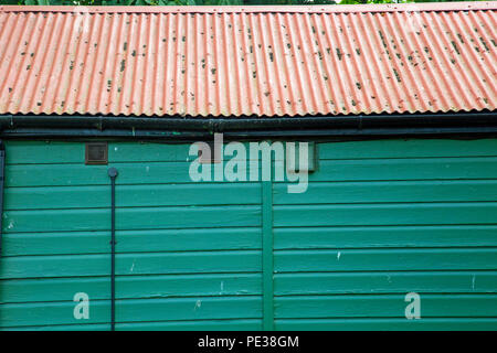 Green cabane en bois avec un toit en tôle ondulée peinte rouge Banque D'Images