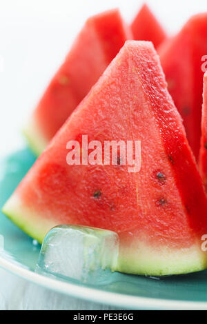 Les tranches de melon sur une plaque bleue avec des cubes de glace. Fond en bois blanc, haute résolution Banque D'Images