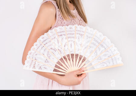 Jeune fille en robe couleur crème dentelle blanche mariage pliage portefeuille ventilateur à main isolé sur fond blanc en studio. Concept de chaleur de l'été. Close up Banque D'Images