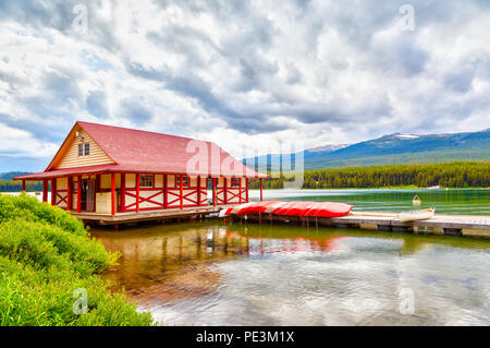 Canoës colorés se trouvent sur le quai à bateaux au Lac Maligne dans le parc national Jasper, Alberta, Canada. Le lac est connu pour les sommets environnants et Banque D'Images