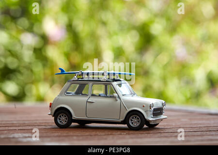 Mini voiture jouet avec sufboard sur le toit du prince pour des vacances sur la plage Banque D'Images
