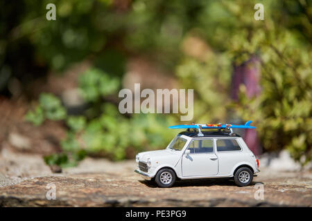 Mini voiture jouet avec sufboard sur le toit du prince pour des vacances sur la plage Banque D'Images