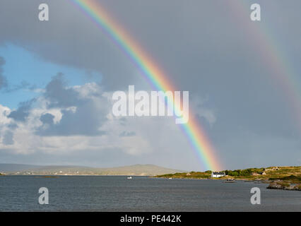 Arc en ciel et blanc cottage by the sea sur la côte du Connemara à l'ouest de l'Irlande Banque D'Images