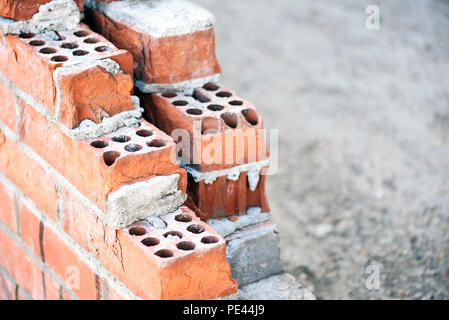Les construisant briques rouges formant un mur en cours de construction au mortier de ciment visible Banque D'Images