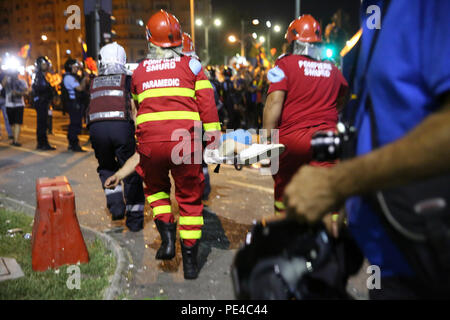Bucarest, Roumanie - 10 août 2018 : Les ambulanciers offrent les premiers soins aux blessés un supporteur de football par des gaz lacrymogènes reçoit lors de la violente anti- Banque D'Images