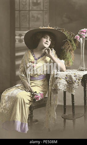 Vintage à la main, teintées, sépia, Edwardian Carte postale montrant une belle femme dans une photo hat. Banque D'Images