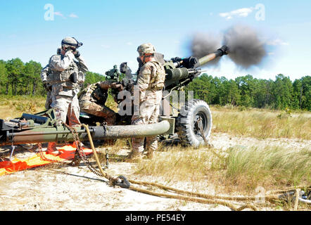 Un équipage du 1er Bataillon du 319th Airborne Field Artillery Regiment, 82nd Airborne Division, tire plusieurs obus de 105mm à partir d'un obusier M119A3 à Fort Bragg, Caroline du Nord, le 5 octobre 2015. L'obusier a été attaqué par un hélicoptère UH-60 Black Hawk dans le cadre d'un raid à deux canons. Les équipages pratiquent des exercices de tir réel, des opérations de chargement d'élingue, la mise en place de l'artillerie et la coordination entre les unités de l'aviation et de l'artillerie pour maintenir l'état de préparation opérationnelle et la compétence au combat dans les exercices aéroportés. Banque D'Images