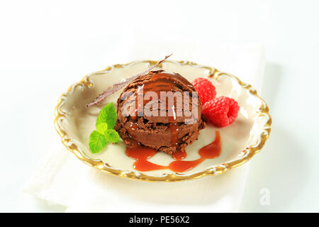 Boule de glace au chocolat avec sauce au caramel et framboises Banque D'Images