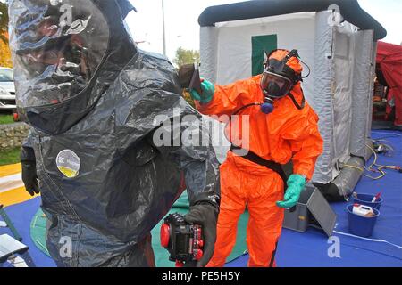 Un pompier belge aide le s.. Shawn McKenna, une réserve de l'armée américaine sous-officier du 773e de l'aide aux civils, au cours de l'équipe de décontamination CBRN en Semaine 2015. (Photo par le personnel. Le Sgt. Rick Scavetta, 7ème commande de soutien de mission) Banque D'Images