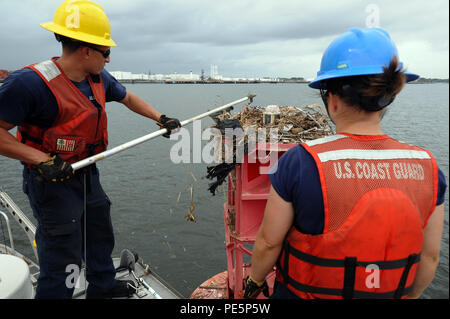 Fireman Carrie Gillespie montres comme maître de 3e classe Kevin Conklin, un technicien de machines de la Garde côtière canadienne à l'équipe d'aides à la navigation New York, frappe un nid d'oiseau sur une bouée le long de la rivière Navesink au New Jersey, le 29 septembre, 2015. L'équipage en poste à New York ANT L'inspection, l'entretien, de service, de positionner avec exactitude et soulager attribué des aides flottantes à la navigation pour assurer la sécurité du transport maritime dans la région. (U.S. Photo de la Garde côtière canadienne par le maître de 3e classe Ali Flockerzi.) Banque D'Images