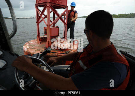 Maître de 2e classe Geoff Haywood observe alors que Fireman Carrie Gillespie nettoie une bouée au large le long de la rivière Navesink au New Jersey, le 29 septembre, 2015. Les hommes et les femmes de New York ANT sont responsables de l'entretien, 96 480 aides principales aides saisonnières et 9 phares majeurs, ce qui permet de garantir la sécurité du transport maritime dans la région. (U.S. Photo de la Garde côtière canadienne par le maître de 3e classe Ali Flockerzi.) Banque D'Images