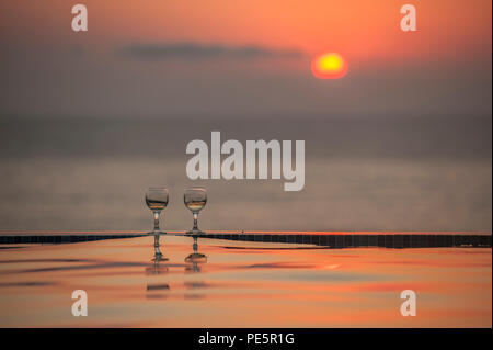 Champagne par une piscine à débordement au coucher du soleil Banque D'Images