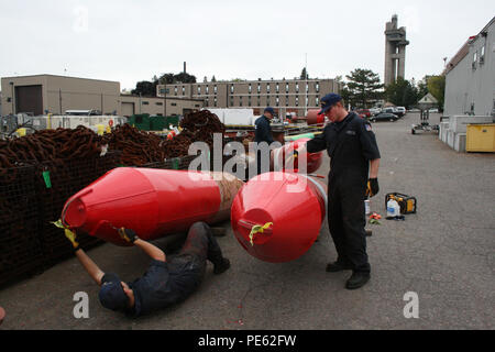 Seaman Jacob Smith et pompiers Timothy Hunter et Eric Mangerilli, membres d'équipage à bord d'un cotre de la Garde côtière canadienne Le nerprun, 100 pieds à l'intérieur des terres en homeported baliseur de Sault Ste. Marie, au Michigan, la peinture plusieurs bouées de glace au port le 2 octobre 2015. Au début de l'hiver, la glace des bouées sont échangés avec les aides lumineuses dans le cadre de l'Opération Récupération de l'automne. (U.S. Photo de la Garde côtière par Seaman Steve Strohmaier) Banque D'Images