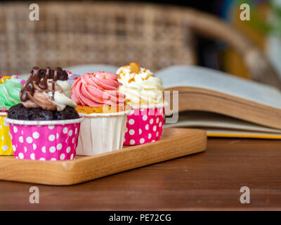 Maison de colorés cupcake sur plateau en bois et le livre ouvert sur la table en bois. Concept de style de vie et vous détendre. Banque D'Images