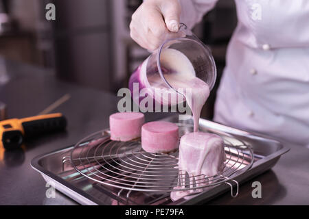 Baker holding cup avec glaçage miroir de mesure pour les gâteaux Banque D'Images