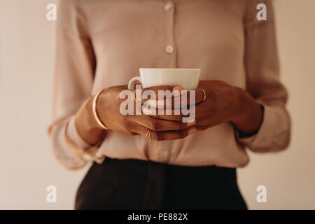 Mid section of businesswoman standing tenant une tasse de café dans les mains. Banque D'Images