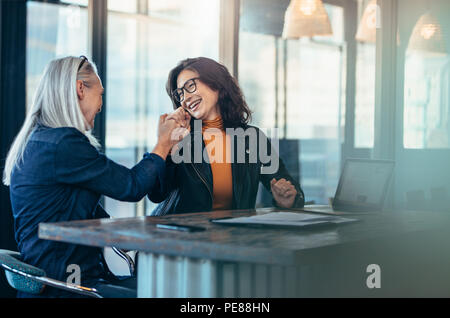 Deux femme donnant à chaque autre un cinq et souriant. Des collègues de bureau se réjouir du succès. Banque D'Images