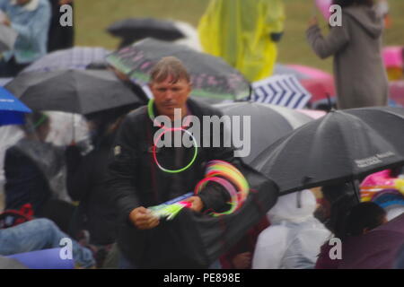 Bâton lumineux vendeur chez British Public orné d'Umbrella et manteaux de pluie à Bristol Balloon Fiesta sur un jour d'été pluvieux. UK. En 2018. Banque D'Images