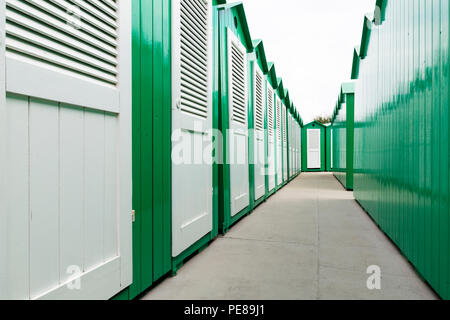 Vue vers le bas une rangée de cabines de plage en bois peint en vert avec portes blanches Banque D'Images