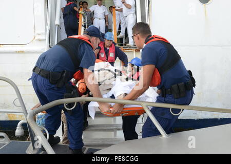 Maître de 2e classe Dustin Gano, extrême gauche, un technicien de machines, assiste le maître de 3e classe Carlos Rodriguez, extrême droite, un technicien de machines, dans le transfert d'un navire de croisière passager en Jacksonville, en Floride, jetées, le 23 octobre 2015. Le passager a été évacué du Carnival Fantasy et transférée aux services d'urgence après avoir subi les symptômes d'une crise cardiaque. (U.S. Photo de la Garde côtière du Maître de 2e classe Anthony L. Soto) Banque D'Images