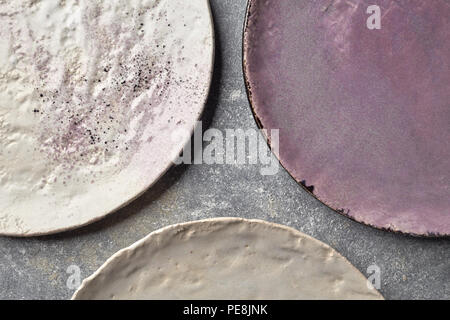 Assiettes en porcelaine décoré en couleurs sur une table de marbre gris. Des plats en céramique fait main vintage. Banque D'Images