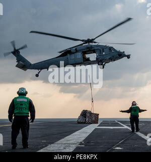 151029-N-OI810-115 EAUX À L'EST DE LA PÉNINSULE CORÉENNE (oct. 29, 2015) Un MH-60S Sea Hawk affecté à l 'île de la mer des Chevaliers de l'Escadron d'hélicoptères de combat (HSC) 25 transferts des fournitures à l'envol de la Marine américaine est que l'avant-déployé porte-avions USS Ronald Reagan (CVN 76) au cours d'un ravitaillement en mer avec commande de transport maritime de marchandises militaires et munitions ship USNS Wally Schirra (T-AKE 8). Ronald Reagan et son aile, l'air carrier Air Wing 5 (CVW), fournir une force prête au combat qui protège et défend les intérêts de la maritime collective aux Etats-Unis et je Banque D'Images