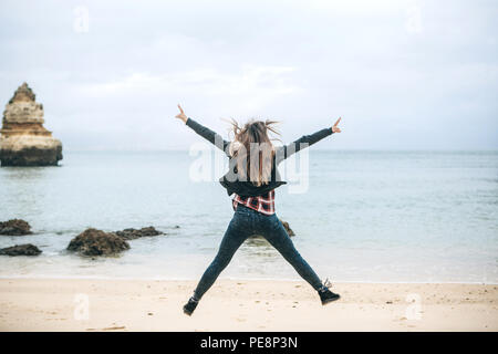 Une jeune fille saute sur la côte atlantique et montre comment elle aime la vie et comment elle est heureuse. Banque D'Images