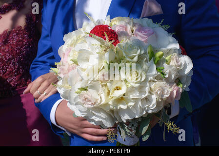 Portrait jeune homme invité au mariage, portant un costume bleu royal et la tenue d'un blanc pâle et bouquet de roses roses, freesias et hortensias Banque D'Images