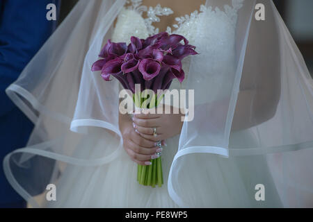 Portrait mariée portait une robe de mariage somptueux avec grand Voile de tulle et tenant une prune sophistiqué des zantedeschias bridal bouquet Banque D'Images